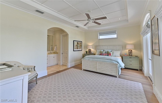 bedroom with visible vents, baseboards, arched walkways, light wood-style floors, and a raised ceiling