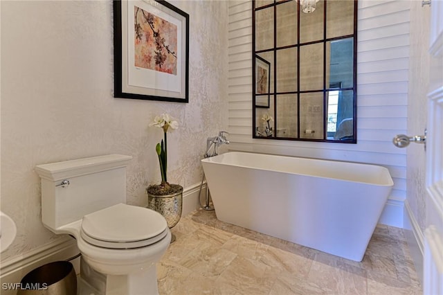 bathroom with toilet and a freestanding bath