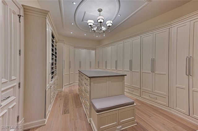 walk in closet with light wood-style flooring and an inviting chandelier