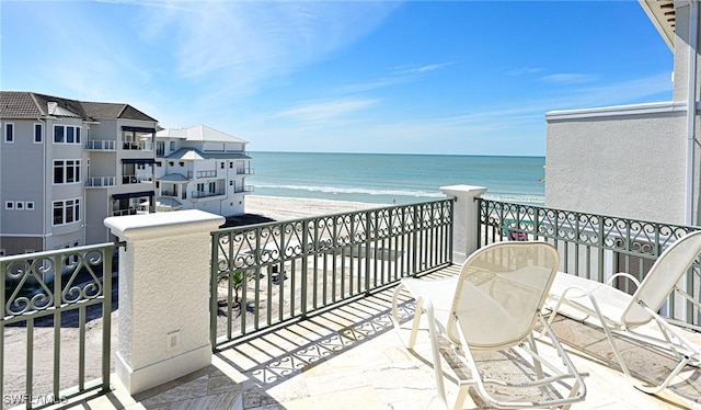 balcony featuring a view of the beach and a water view