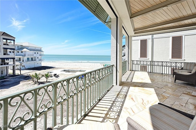 balcony featuring a view of the beach and a water view