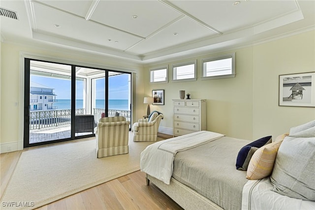 bedroom featuring a tray ceiling, visible vents, wood finished floors, and access to exterior