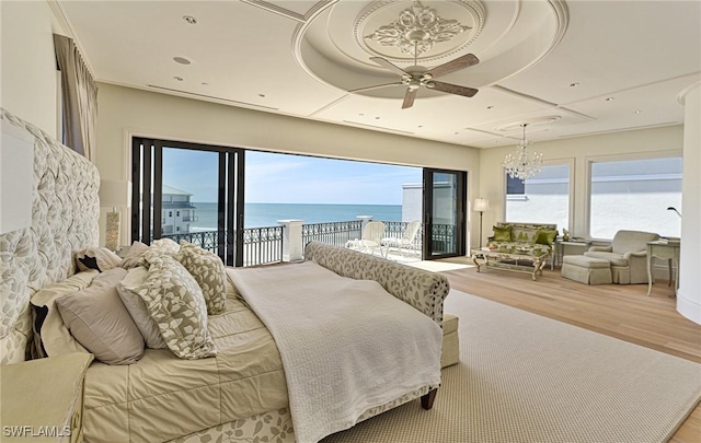 bedroom featuring a water view, access to outside, wood finished floors, recessed lighting, and an inviting chandelier