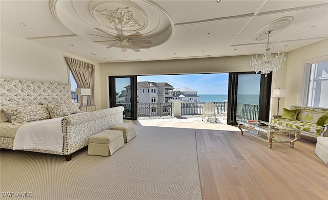 bedroom with access to exterior, multiple windows, wood finished floors, and a water view