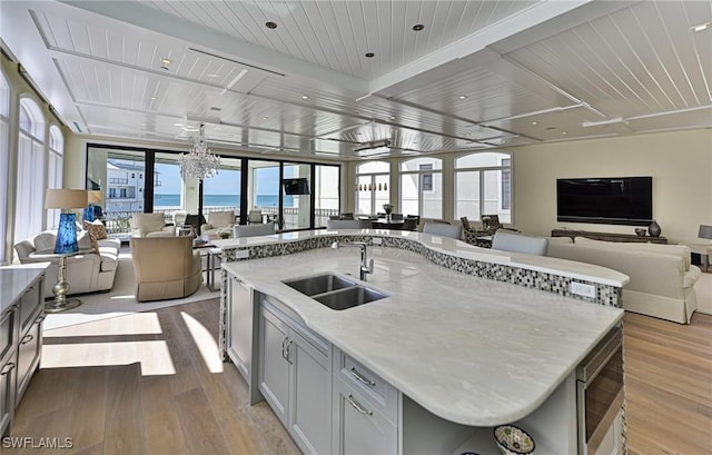 kitchen with a center island with sink, light wood-type flooring, open floor plan, and a sink