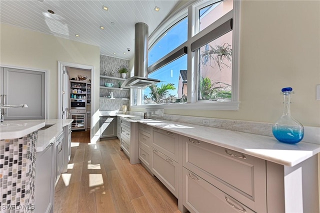 kitchen featuring oven, light wood-type flooring, a sink, open shelves, and island range hood