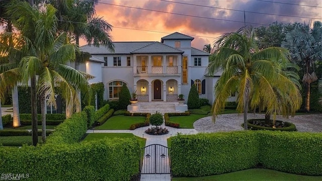 mediterranean / spanish-style house featuring driveway, a gate, a balcony, and stucco siding