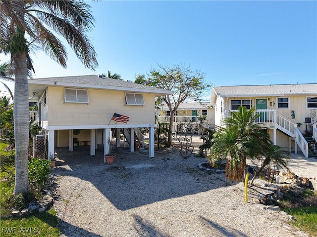 rear view of house with gravel driveway, a carport, and stairway