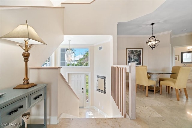 entryway featuring plenty of natural light, ornamental molding, and a notable chandelier