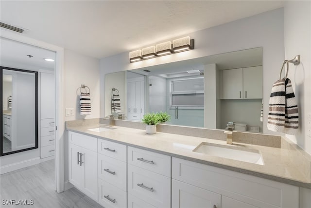 bathroom with a closet, visible vents, a sink, and double vanity