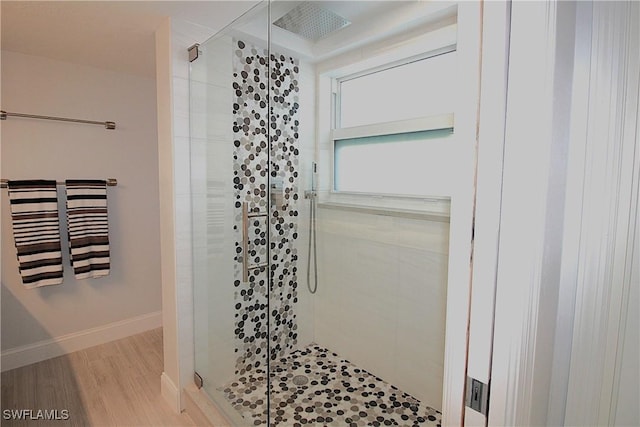 bathroom featuring a shower stall, baseboards, and wood finished floors