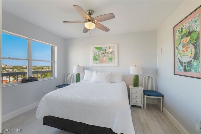 bedroom featuring a ceiling fan, light wood-style flooring, and baseboards