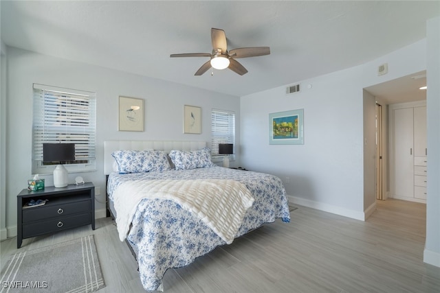 bedroom featuring ceiling fan, light wood-style flooring, visible vents, and baseboards