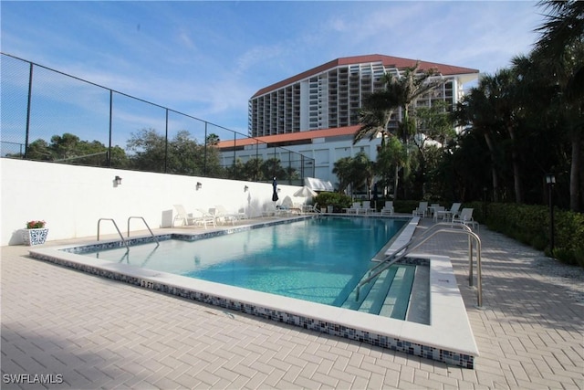 pool with a patio area and fence