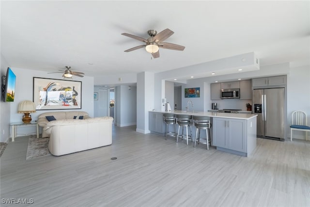 living area with light wood-style floors, baseboards, and a ceiling fan