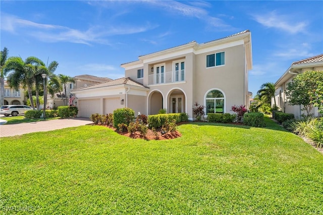 mediterranean / spanish home featuring stucco siding, concrete driveway, a front yard, a garage, and a balcony