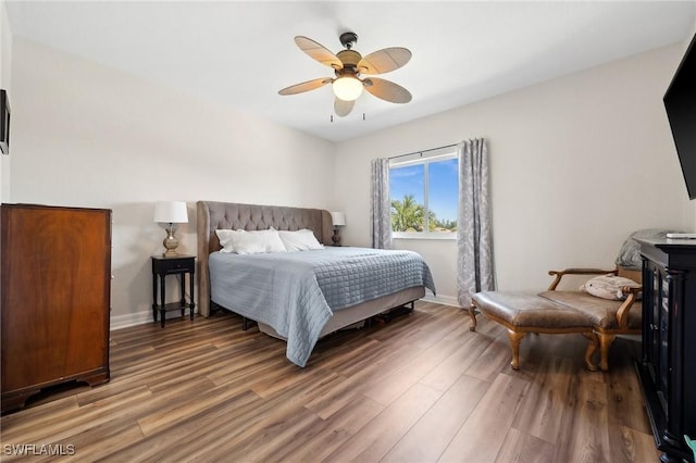 bedroom with a ceiling fan, wood finished floors, and baseboards