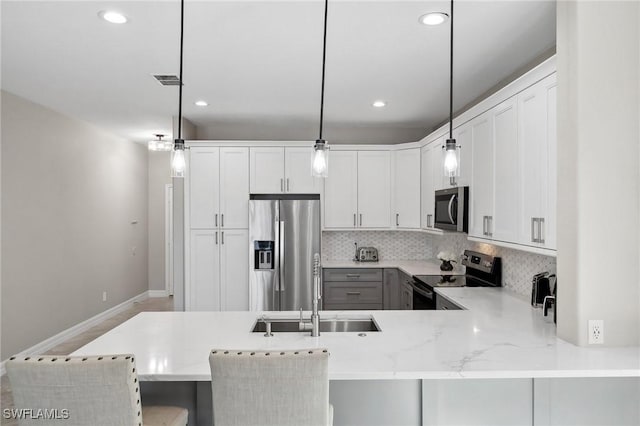 kitchen featuring decorative backsplash, a peninsula, stainless steel appliances, and a sink