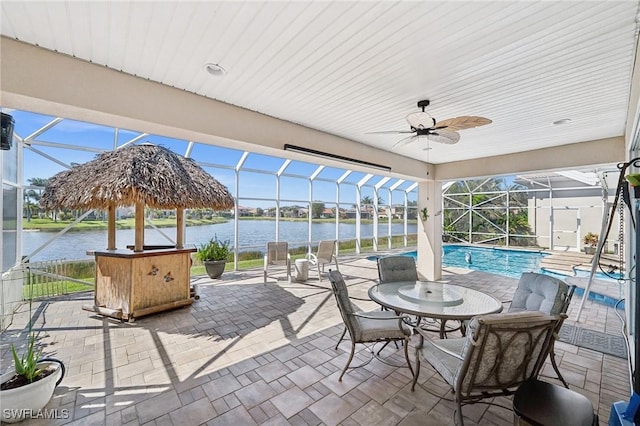 view of patio featuring an outdoor pool, glass enclosure, a water view, and ceiling fan