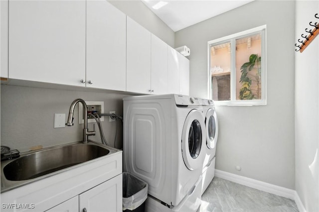 laundry area featuring a sink, baseboards, cabinet space, and separate washer and dryer