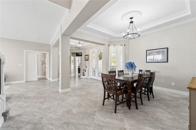 dining area with a notable chandelier, crown molding, a raised ceiling, and baseboards