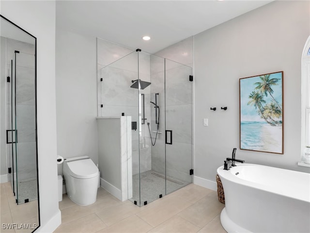 bathroom featuring tile patterned flooring, baseboards, toilet, a stall shower, and a freestanding tub