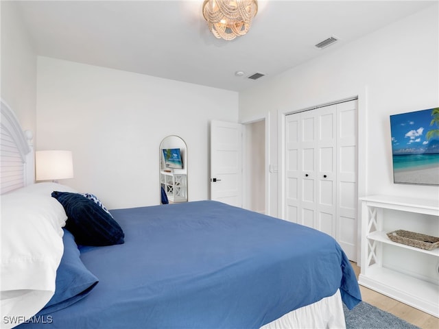 bedroom featuring a closet, visible vents, and wood finished floors