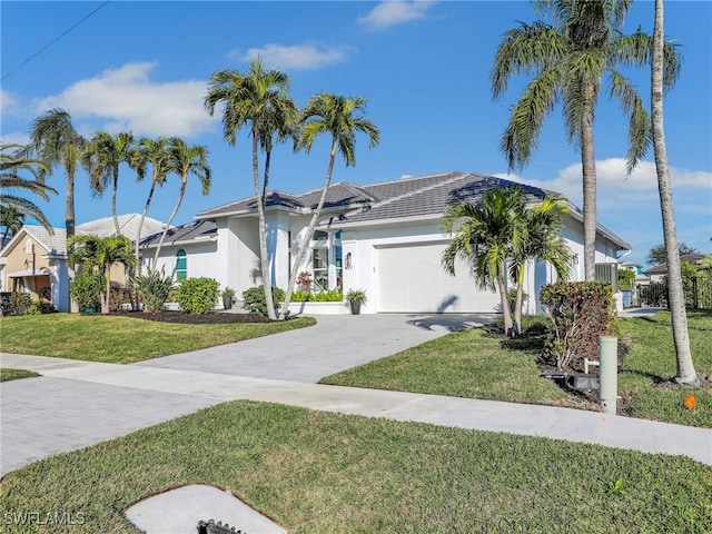 view of front of house with a front lawn, a tiled roof, concrete driveway, stucco siding, and an attached garage