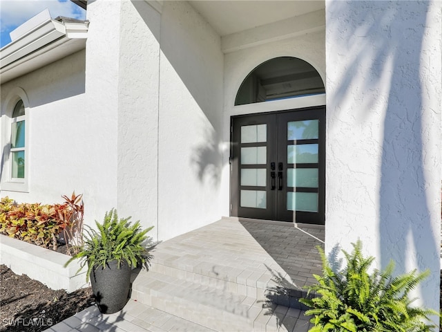 property entrance featuring stucco siding and french doors