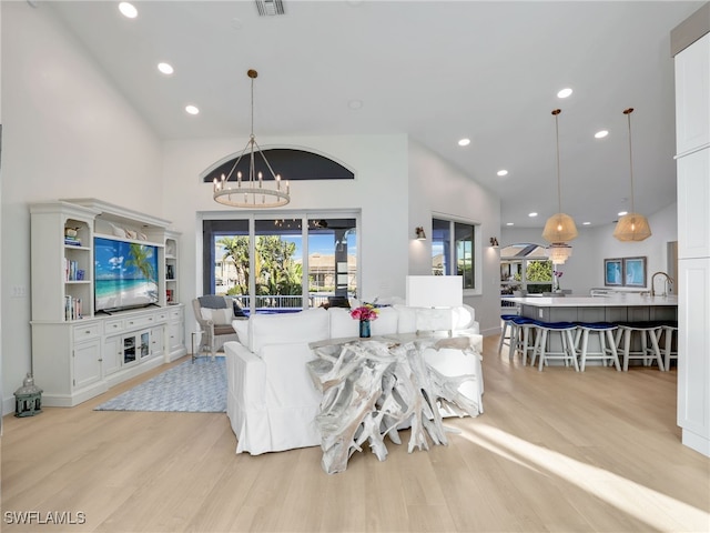 living area with an inviting chandelier, plenty of natural light, and light wood-style floors