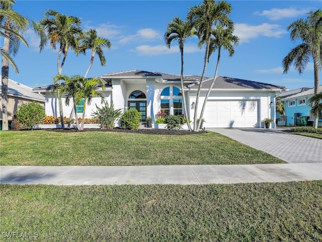 view of front of property featuring decorative driveway, a front lawn, an attached garage, and stucco siding