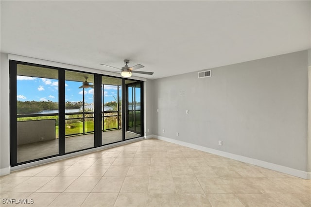 tiled spare room with a wall of windows and ceiling fan