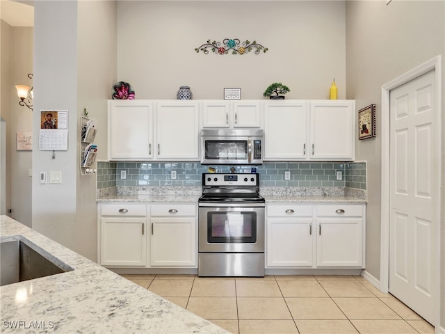 kitchen with appliances with stainless steel finishes, white cabinets, and light stone counters