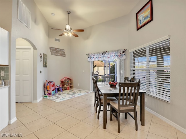 dining space featuring light tile patterned floors, ceiling fan, and a high ceiling