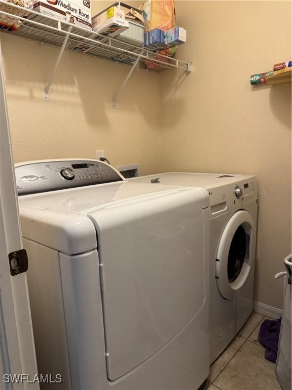 laundry area with laundry area, light tile patterned floors, baseboards, and separate washer and dryer