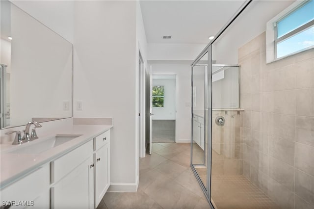 bathroom with vanity, a wealth of natural light, and a tile shower