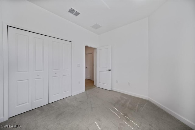 unfurnished bedroom featuring light carpet and a closet