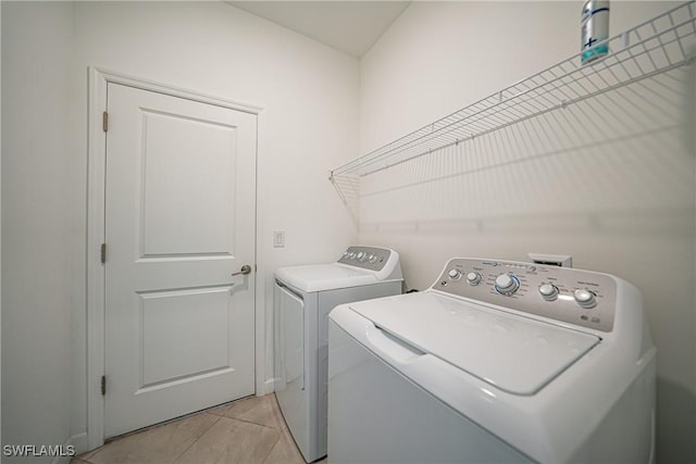 laundry area featuring washing machine and dryer and light tile patterned flooring