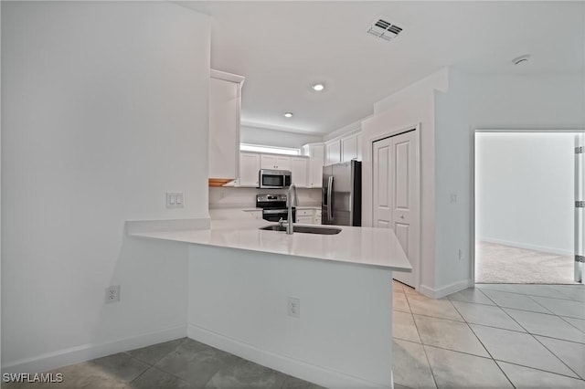 kitchen featuring sink, white cabinets, light tile patterned floors, kitchen peninsula, and stainless steel appliances