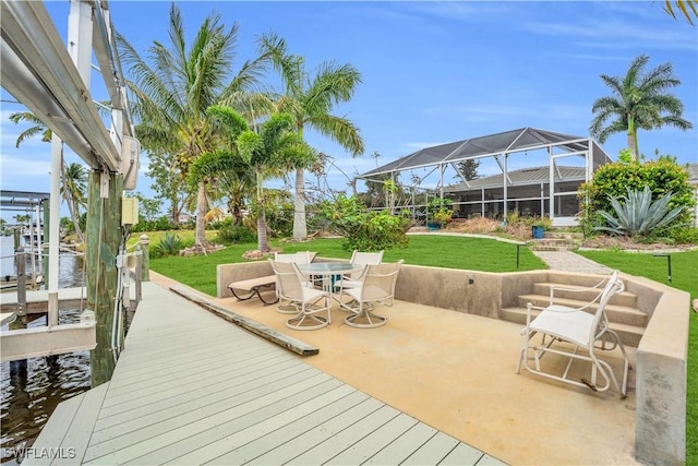 wooden terrace featuring a lawn, a boat dock, a lanai, a water view, and outdoor dining space