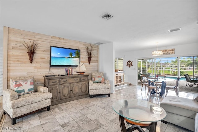 living room featuring an accent wall, wood walls, and visible vents