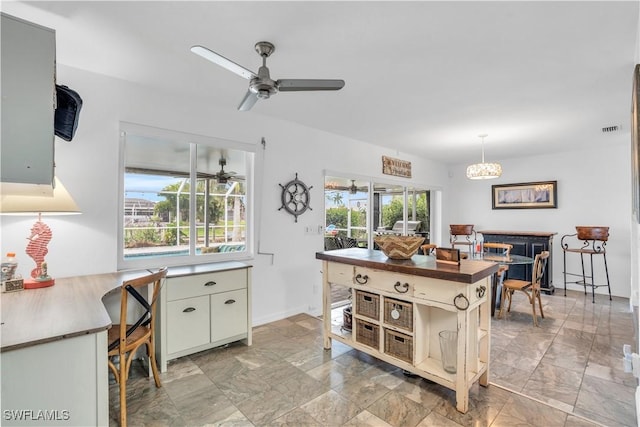 kitchen with ceiling fan with notable chandelier, plenty of natural light, dark countertops, and visible vents