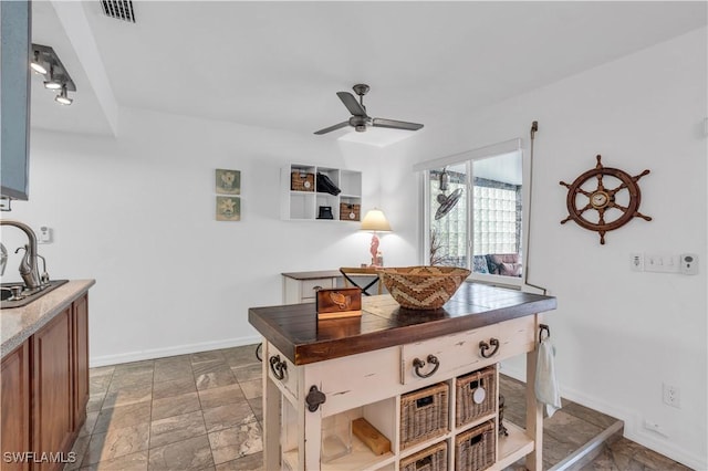 kitchen with baseboards, visible vents, dark countertops, ceiling fan, and a sink