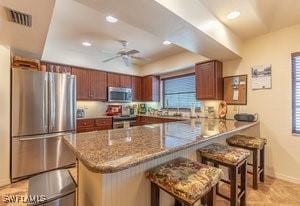595 103rd Ave, Naples, FL 34108 - kitchen featuring visible vents, a peninsula, baseboards, a breakfast bar area, and appliances with stainless steel finishes