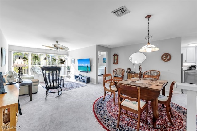 dining room with a ceiling fan, visible vents, light carpet, and baseboards