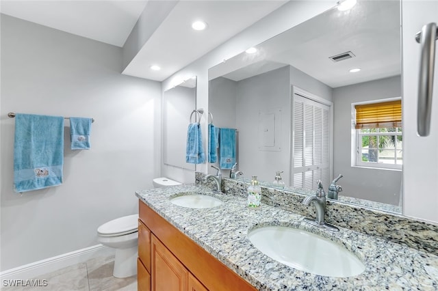 bathroom with toilet, double vanity, a sink, and visible vents