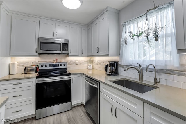 kitchen featuring light countertops, appliances with stainless steel finishes, a sink, and white cabinetry