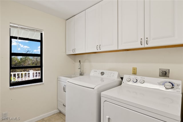 clothes washing area featuring cabinet space, light tile patterned floors, baseboards, washing machine and clothes dryer, and a sink