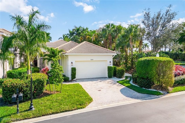 mediterranean / spanish home featuring a garage and a front lawn