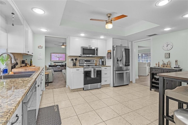 kitchen featuring stainless steel appliances, a raised ceiling, sink, and white cabinets